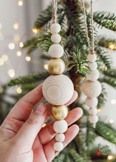 a hand holding a christmas ornament in front of a tree