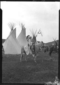 an old black and white photo of native americans on horseback with teepees in the background