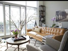 a living room filled with lots of furniture and large windows overlooking a cityscape