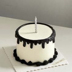 a white and black cake with a single candle on top