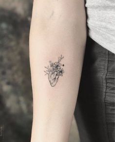 a heart tattoo on the arm with flowers and leaves in it, as well as an arrow