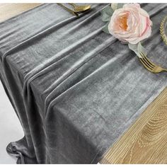 a close up of a table with a silver cloth and gold place settings on it