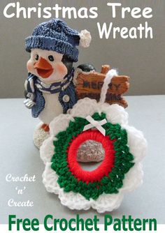 a crocheted christmas tree ornament with a snowman holding a wreath