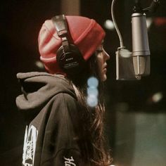 a woman with headphones on is in front of a microphone and wearing a hoodie