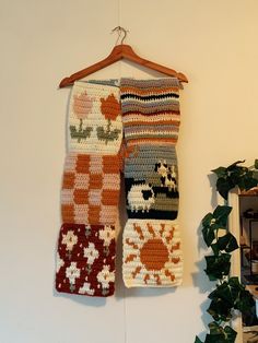 three crocheted towels hanging on a wall next to a potted green plant