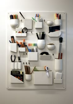 a white wall mounted on the side of a wall filled with office supplies and pens