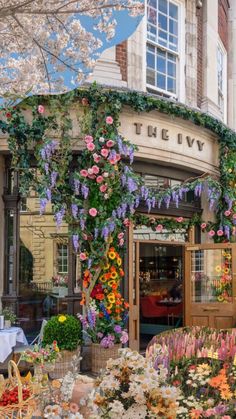 the ivy is covered with flowers and hanging from it's sides in front of a restaurant