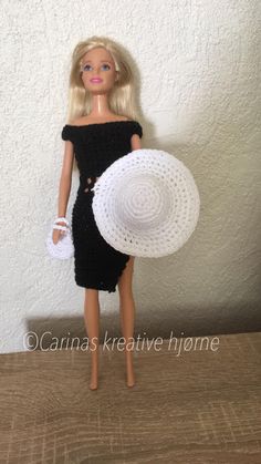 a doll with a white hat and black dress is standing in front of a wall