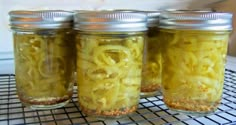 four jars filled with pickled onions sitting on a rack