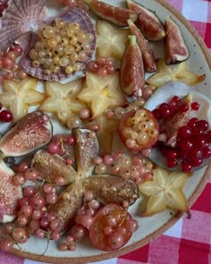 a plate full of fruit and shells on a checkered tablecloth with red gingham cloth