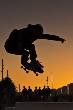 a skateboarder is doing a trick in the air at sunset or sunrise time