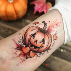 a woman's arm with a pumpkin and hearts tattoo on the left side of her arm