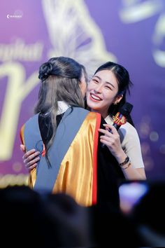 two women hugging each other on stage