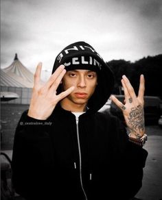 a man in a black hoodie holding up two fingers