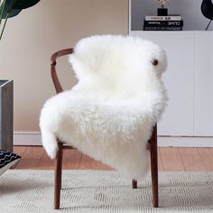 a chair with a white sheepskin seat cover on it's back in a living room