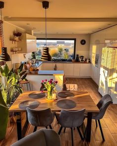 a dining room table with chairs and a vase filled with flowers on top of it