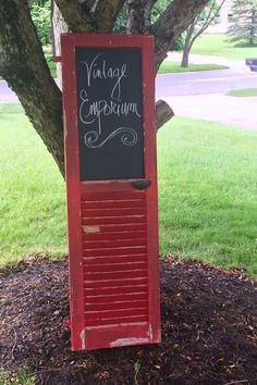 a sign that is on the side of a tree in front of a grass field