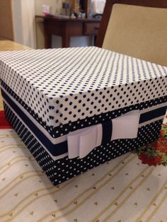 a box sitting on top of a table covered in black and white polka dot fabric