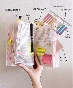 a person holding an open book with notes and pens attached to it, labeled in words