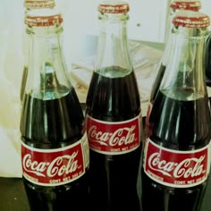 three coca cola bottles sitting on top of a table