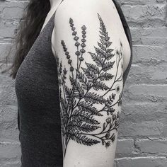 a black and white photo of a woman's arm with a fern tattoo on it