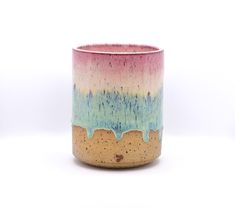 a ceramic cup with blue, pink and yellow glazes on it's side