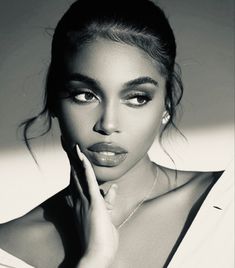 a black and white photo of a woman with her hand on her face, looking at the camera