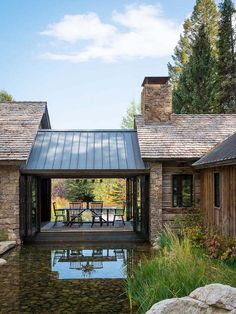 a house with a pond in front of it and stone walls around the back yard