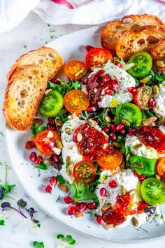 a white plate topped with salad and bread on top of a marble table next to a napkin