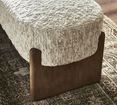 a footstool made out of wood and fabric on a rug in a living room