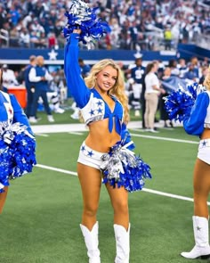 two cheerleaders in blue and white outfits at a football game