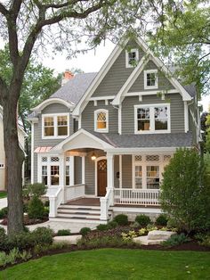 a gray house with white trim and two story windows on the second floor is surrounded by trees