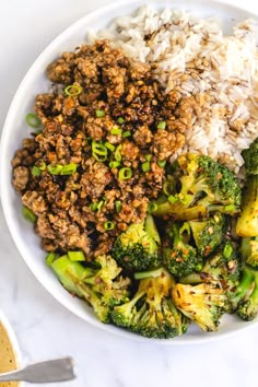 a white bowl filled with meat and broccoli on top of a marble counter