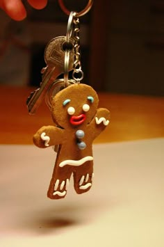 a gingerbread man keychain is being held by a person with a pair of keys