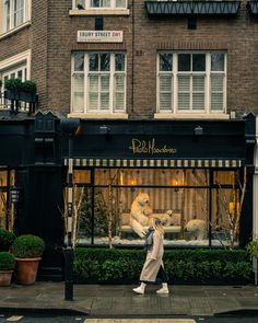 a woman walking down the street in front of a store