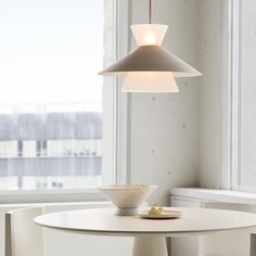 a white table and chairs in front of a window with a bowl on the table