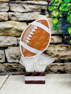 a football trophy sitting on top of a table next to a brick wall and potted plant