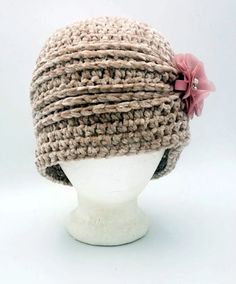 a white mannequin head wearing a crochet hat with pink flowers on it