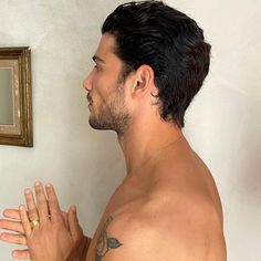 a man with no shirt standing in front of a mirror and holding his hands together