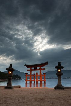 three lanterns are lit up in front of a body of water