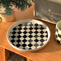 a black and white checkered plate sitting on top of a wooden table next to a radio