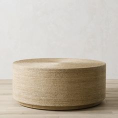 a large round basket sitting on top of a wooden table next to a white wall