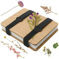 a wooden notebook with black straps and flowers on the cover, surrounded by other items