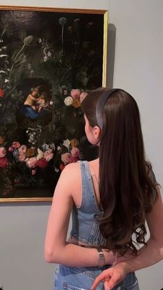 a woman standing in front of a painting with flowers on it's wall and wearing a headband