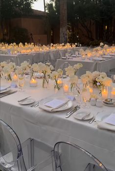 the tables are set with white flowers and candles for an elegant wedding reception at dusk