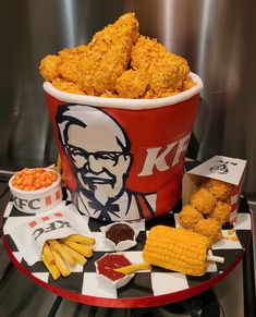 a large bucket filled with fried food next to corn on the cob and ketchup