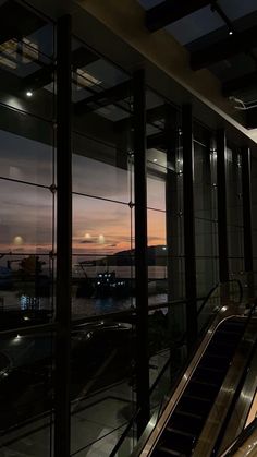 an escalator in front of a window at night with the sun going down