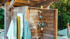 an outdoor shower area with towels hanging on the wall and other items in front of it