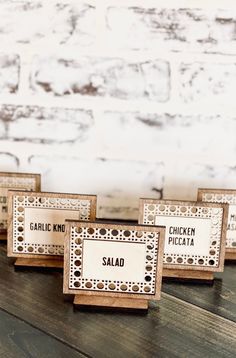 four small wooden signs sitting on top of a table next to a white brick wall