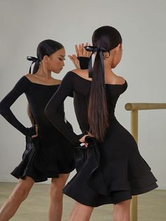 two young women in black dresses are dancing with their hands on their hipss and one is wearing a bow